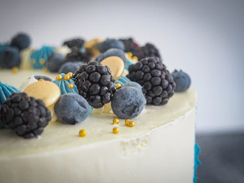Close-up of a beautifully decorated modern minimalist cake with fresh berries on top.