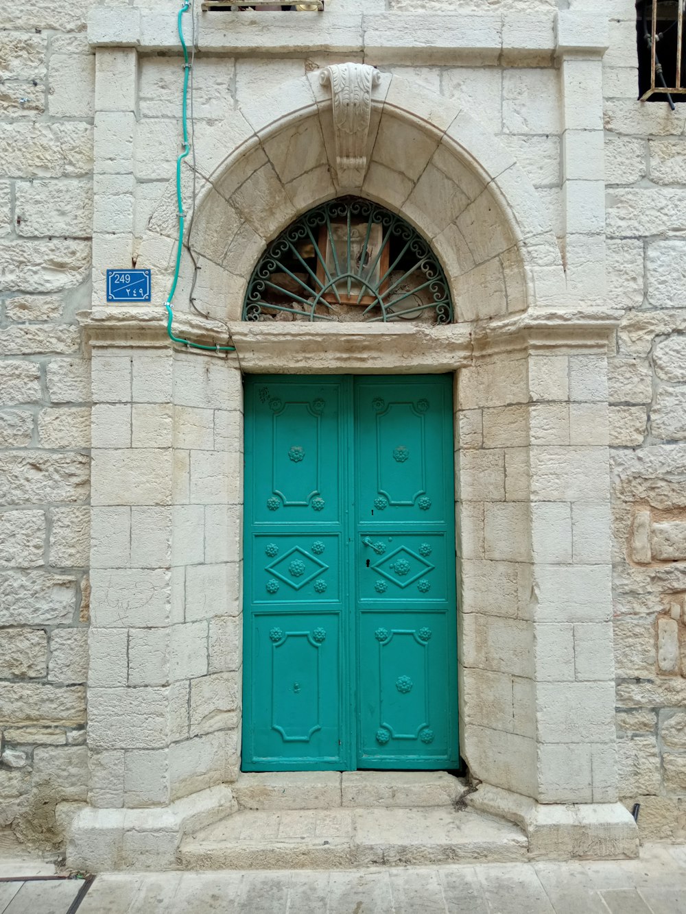 a green door is in front of a stone building