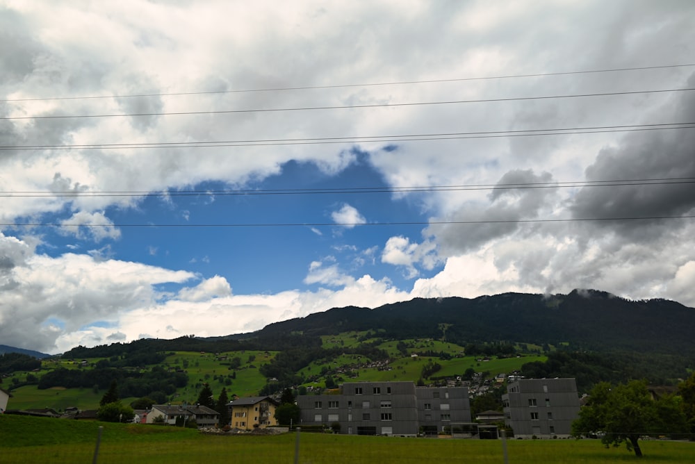 a green field with houses and mountains in the background