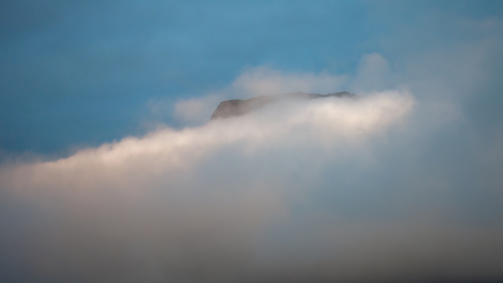 a mountain in the clouds with a blue sky in the background