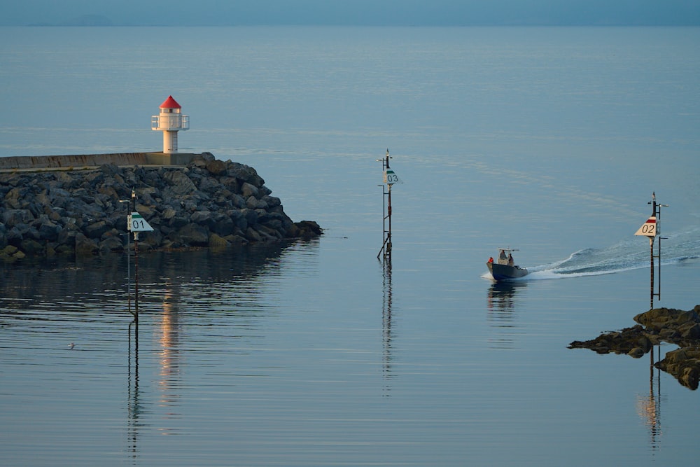 a small boat traveling past a light house