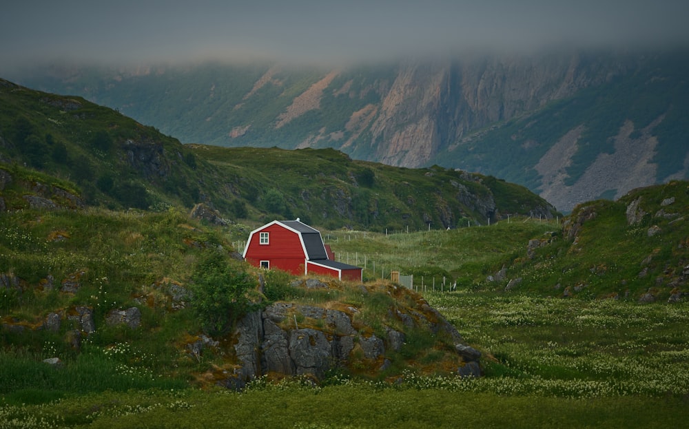 a red barn sits on a grassy hill