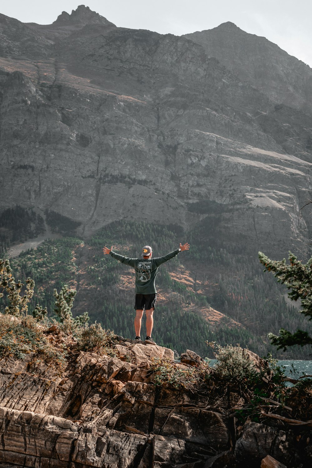 a man standing on top of a mountain with his arms wide open