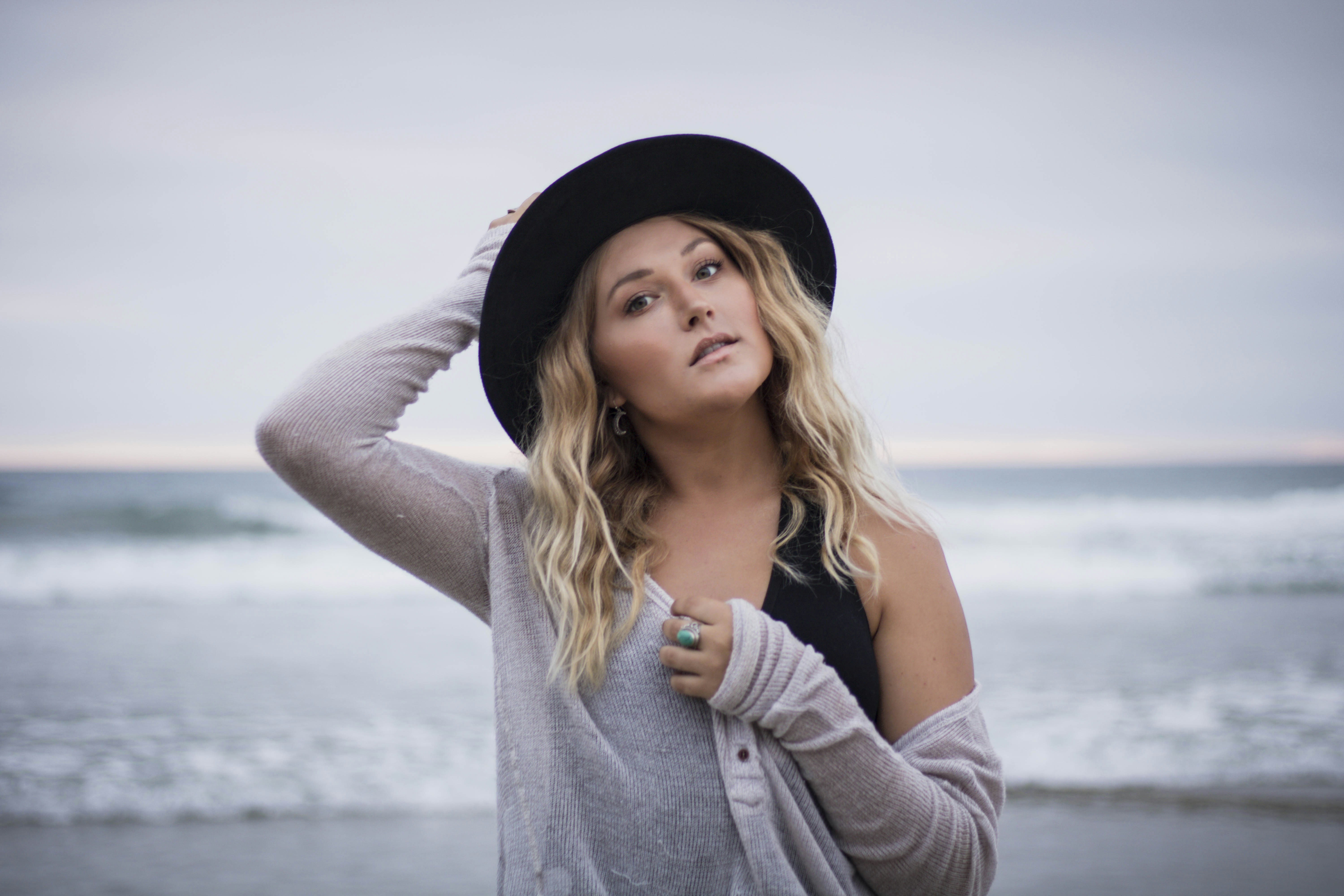a woman wearing a hat standing on a beach