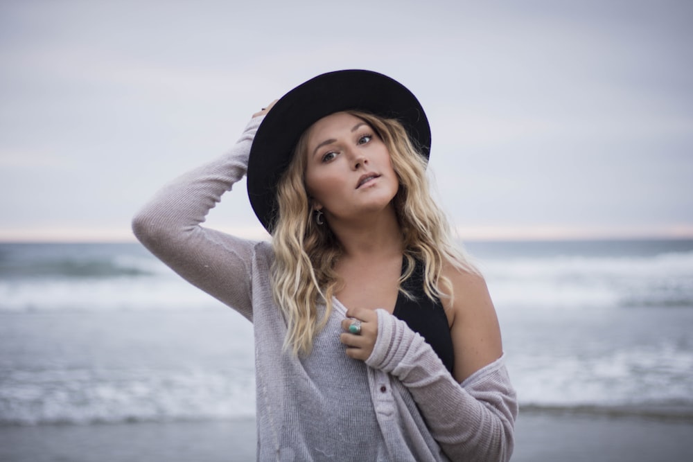 a woman wearing a hat standing on a beach