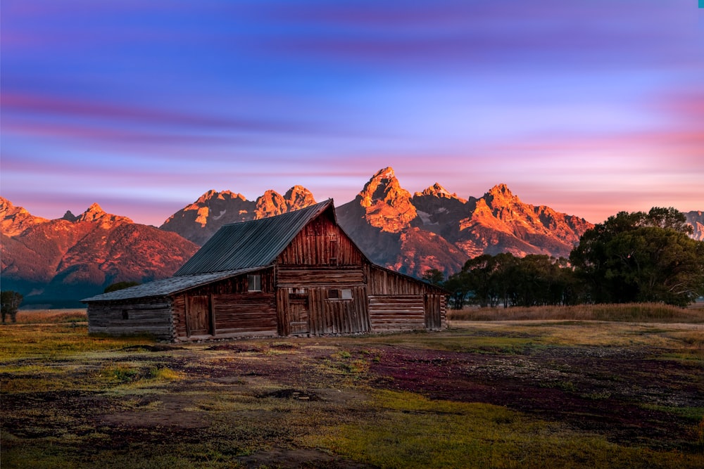 a barn in a field with mountains in the background