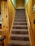 A carpeted staircase is flanked by wooden walls, leading up to a closed wooden door at the top.