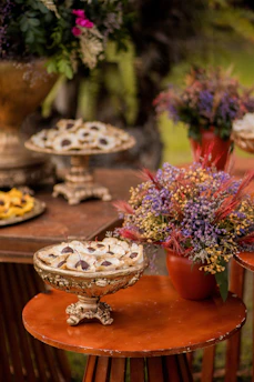 Close-up of colorful tropical bite-size desserts arranged on a rustic wooden table with vibrant leaves around.