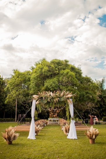 Elegant wedding arch adorned with soft white flowers and greenery in a garden setting.