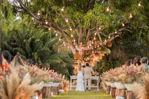 a bride and groom standing under a tree