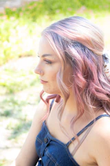 Young woman with a flowing lavender ombre hairstyle smiling outdoors.