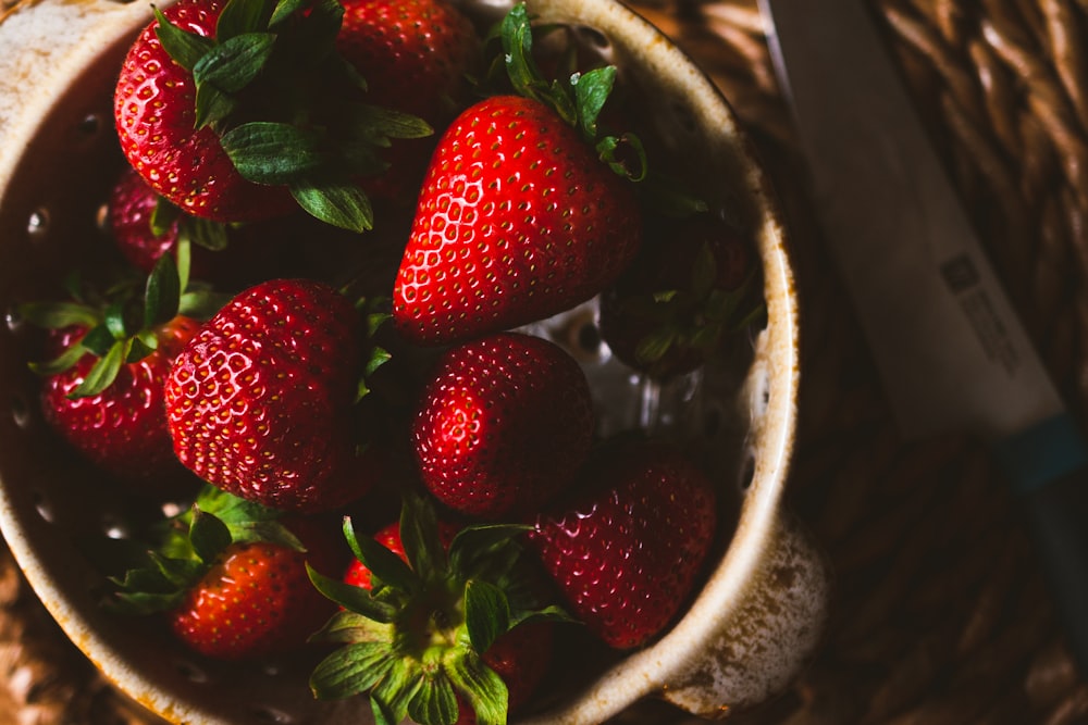 a bowl of strawberries on a wicker table