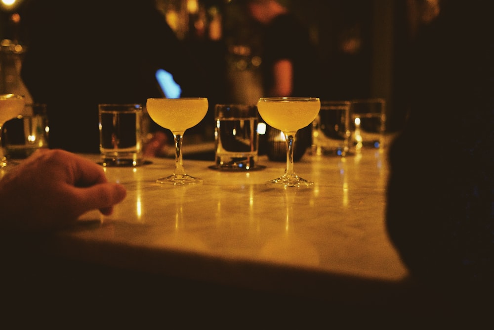 a person sitting at a bar with several glasses of alcohol