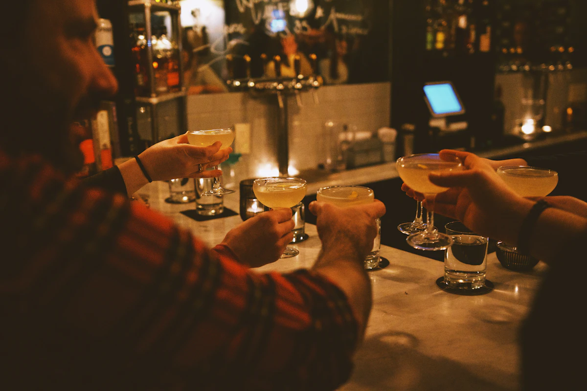 Freunde stoßen in einer Bar mit Getränken an als Symbol für einen rauchfreien Abend trotz Alkohol