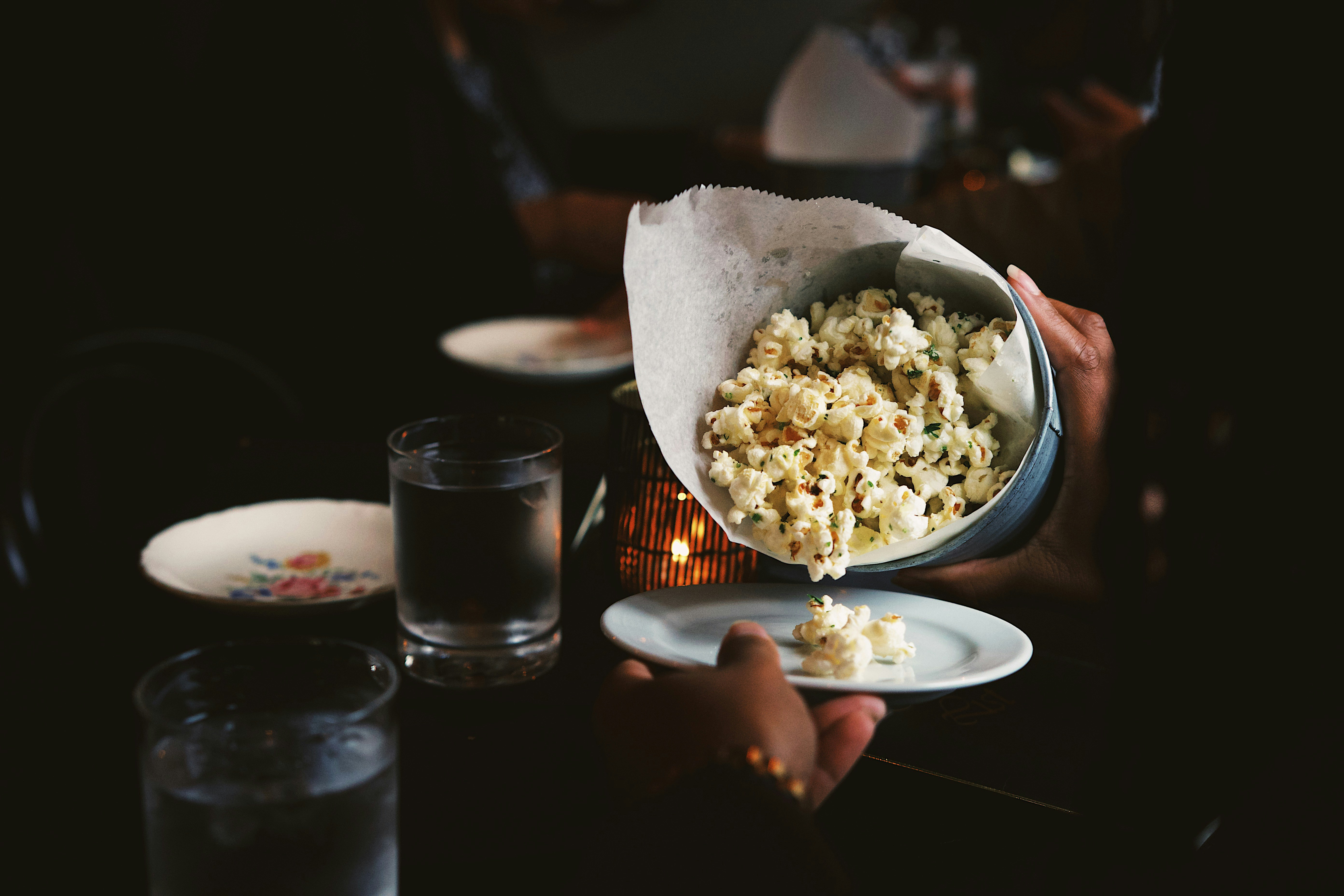 a person holding a bowl of popcorn over a plate