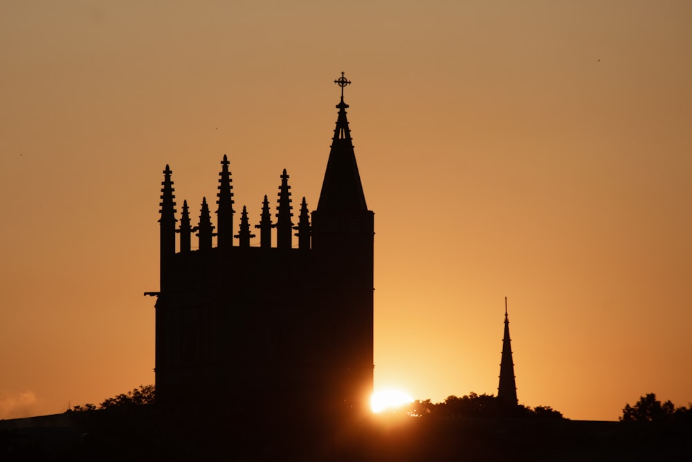 the sun is setting behind a church steeple