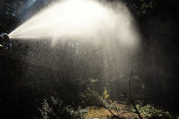 Close-up of a modern thermal fogging machine in use, emitting mist in a green outdoor setting
