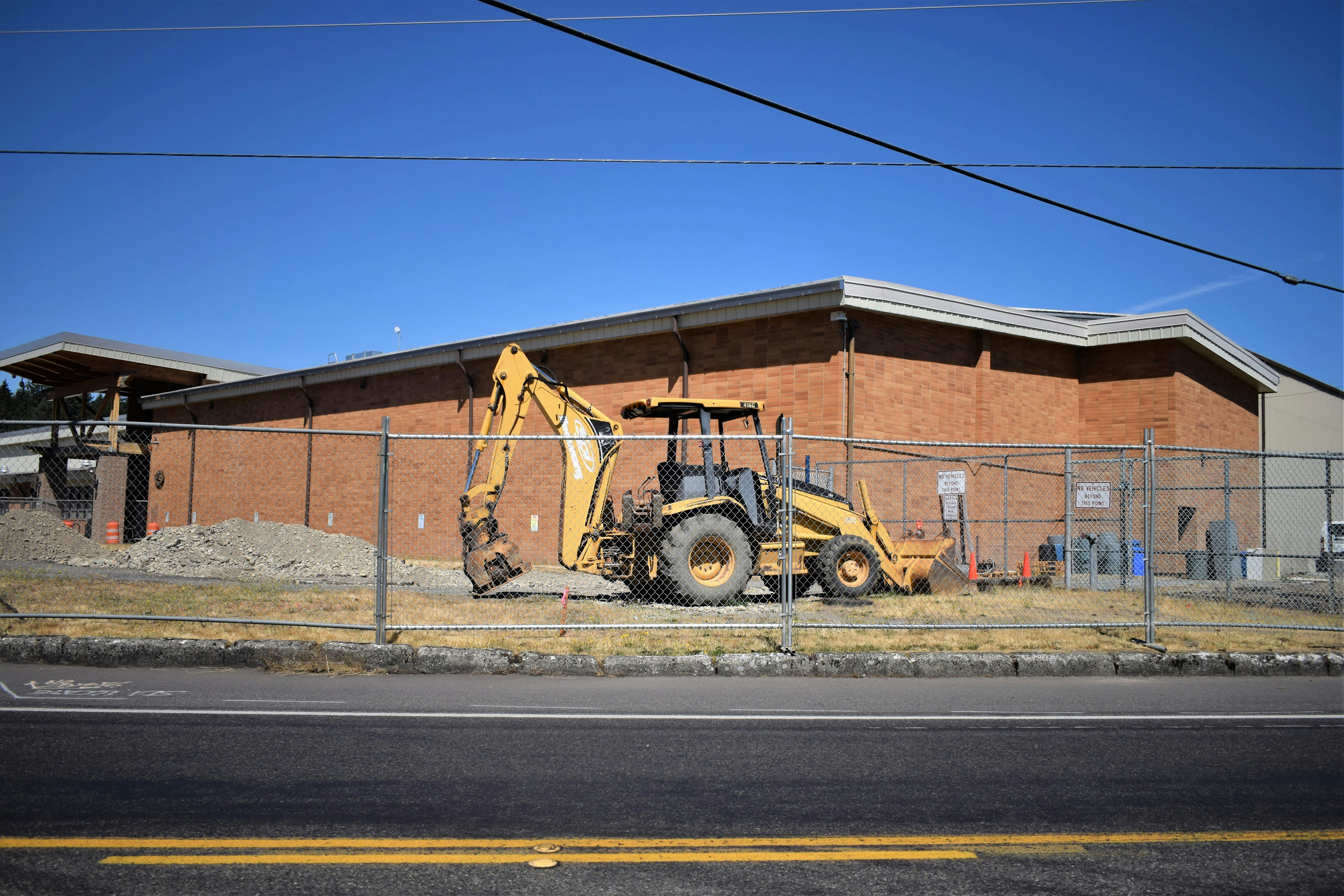 a bulldozer parked in front of a building behind a fence