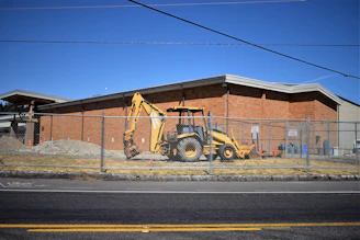 a bulldozer parked in front of a building behind a fence