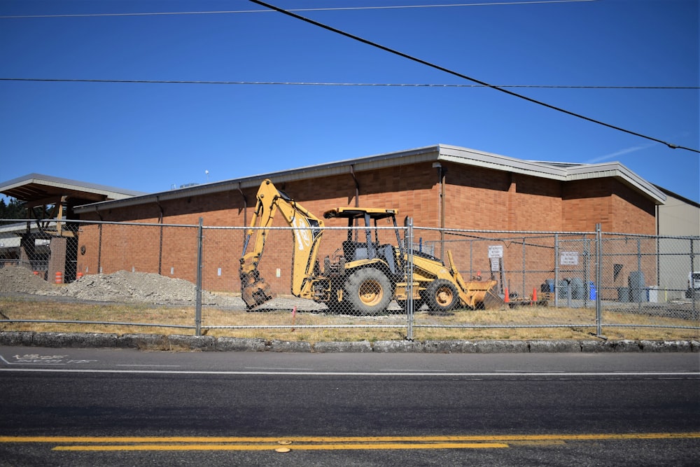 a bulldozer parked in front of a building behind a fence