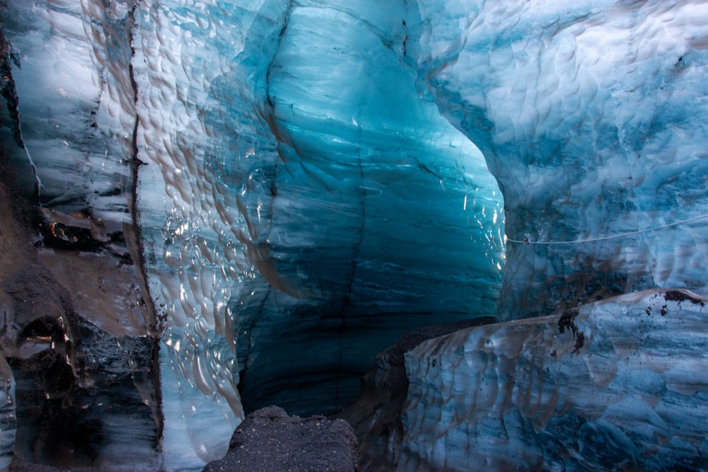 a large blue ice cave with a man standing in it