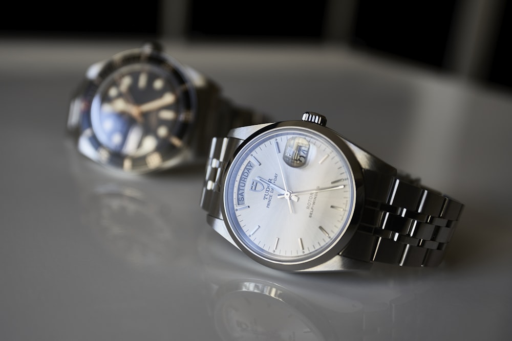 two watches sitting on a table next to each other