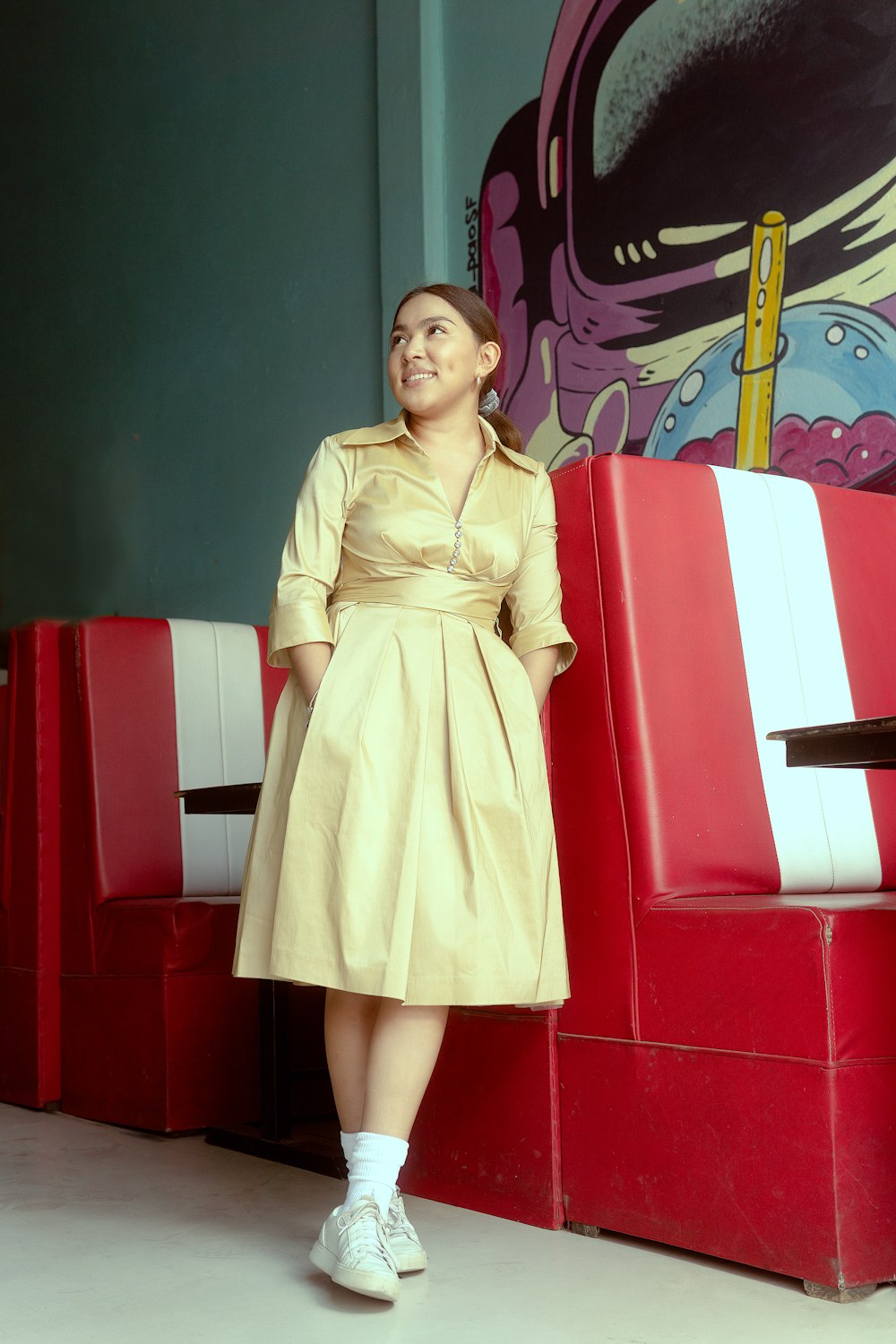 a woman in a tan dress standing in front of some red and white booths