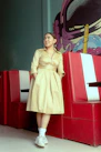 a woman in a tan dress standing in front of some red and white booths