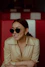 a woman wearing sunglasses sitting in a booth