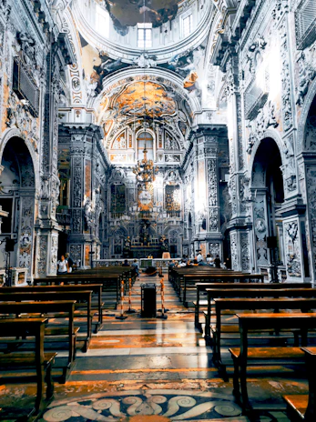 Interior shot of the Basilica di Sant'Anastasia al Palatino showing ornate frescoes and wooden pews bathed in soft light.