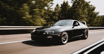 A sleek car influencer posing next to a luxury sports car on an open highway.