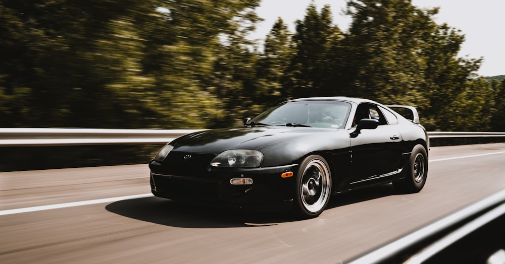 a black sports car driving down the road