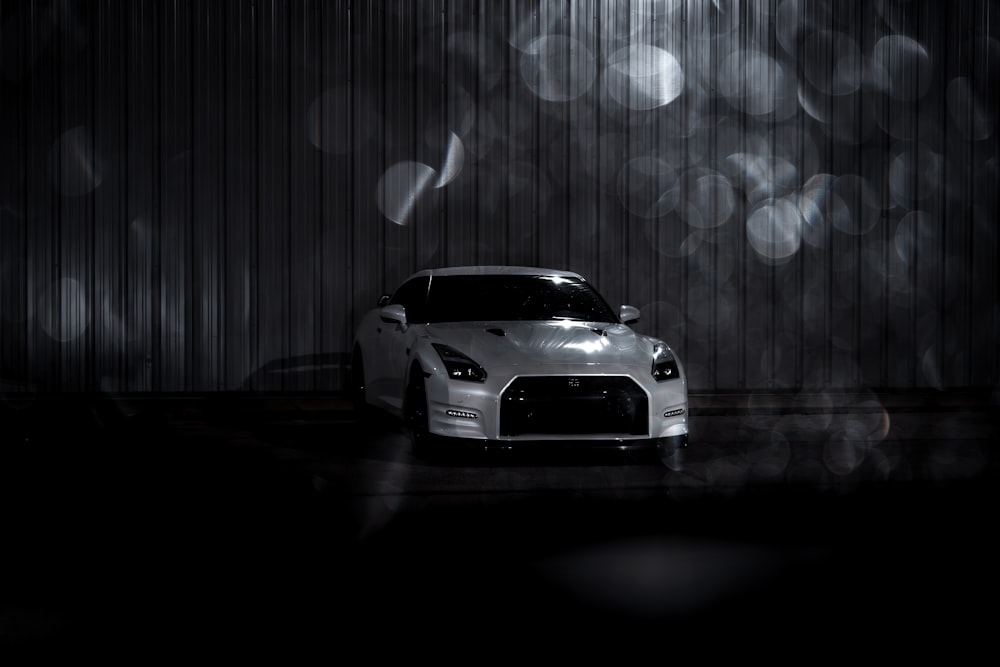 a white sports car parked in front of a wall