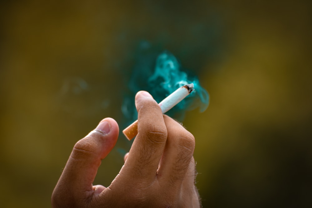 a person holding a cigarette in their hand