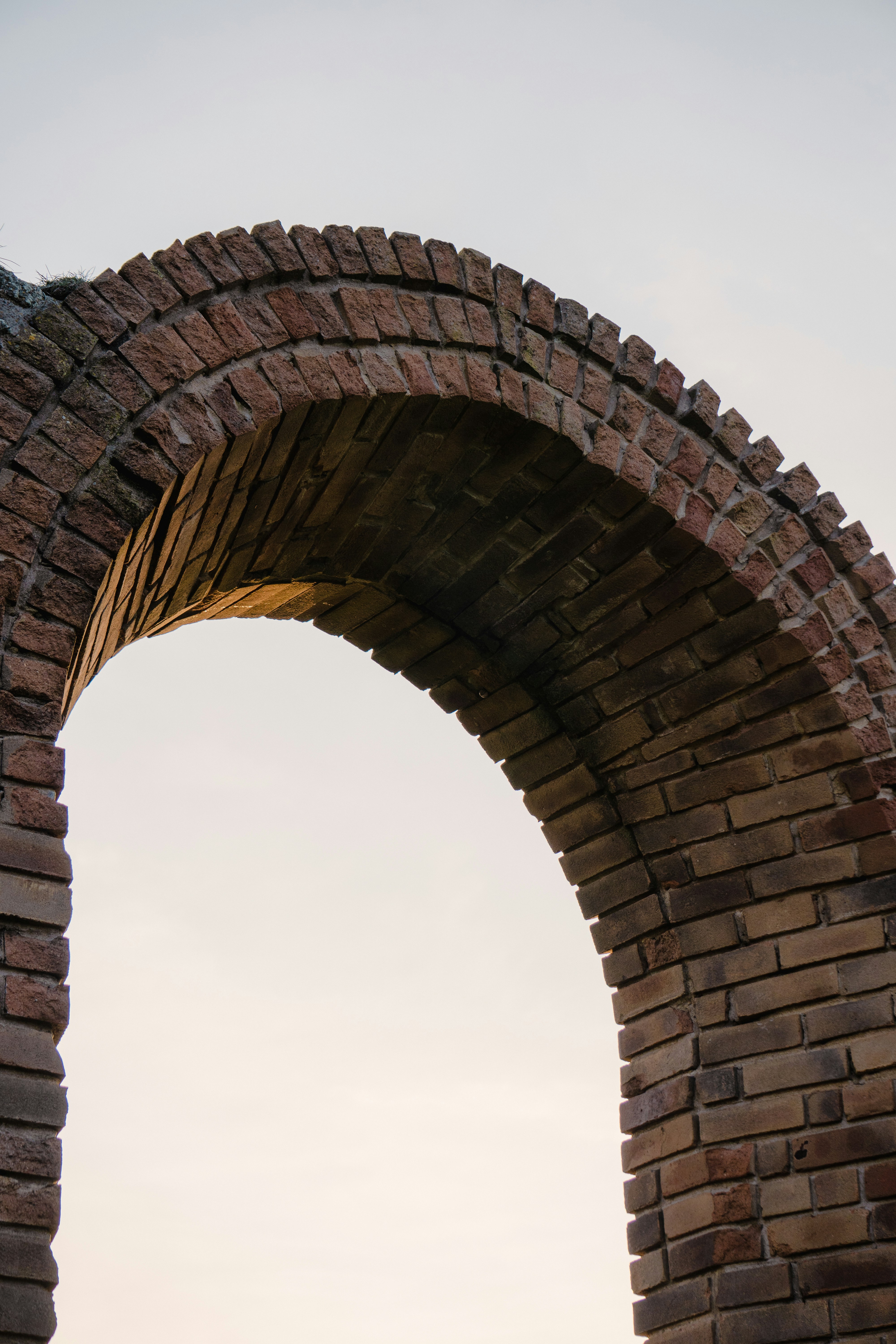 um arco em uma parede de tijolos com um céu no fundo