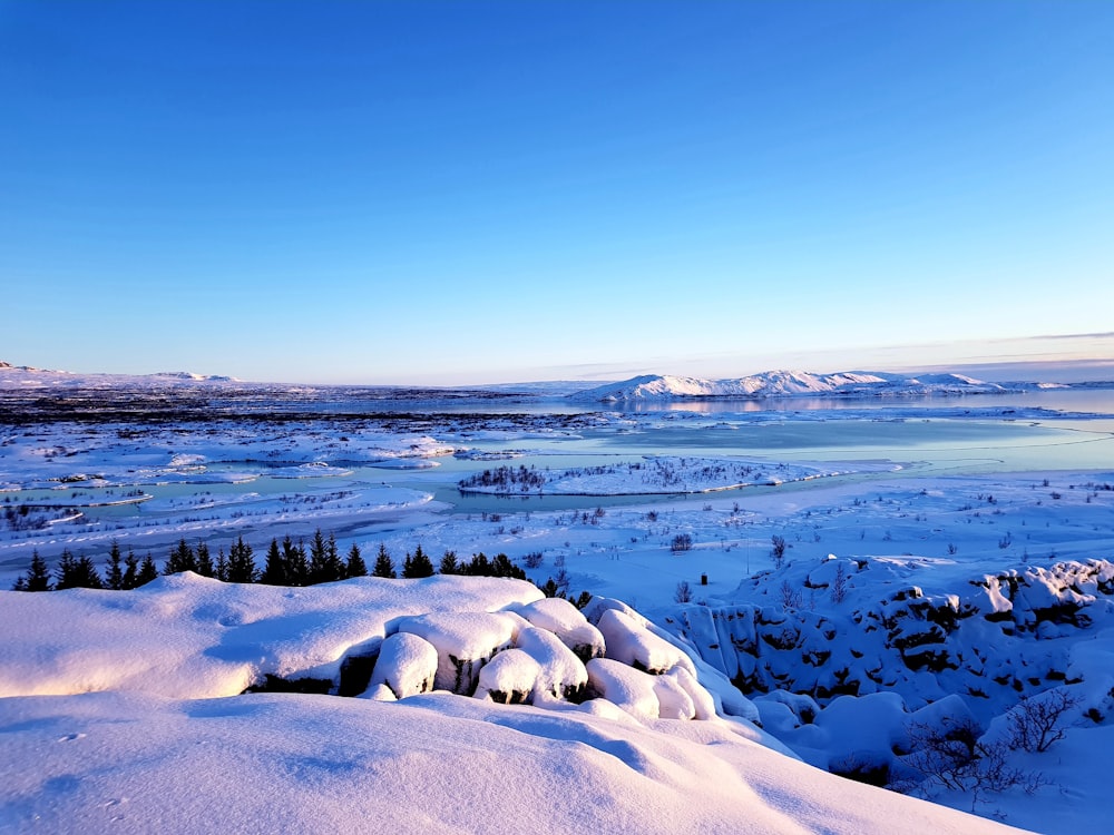 eine verschneite Landschaft mit einem See und Bergen im Hintergrund