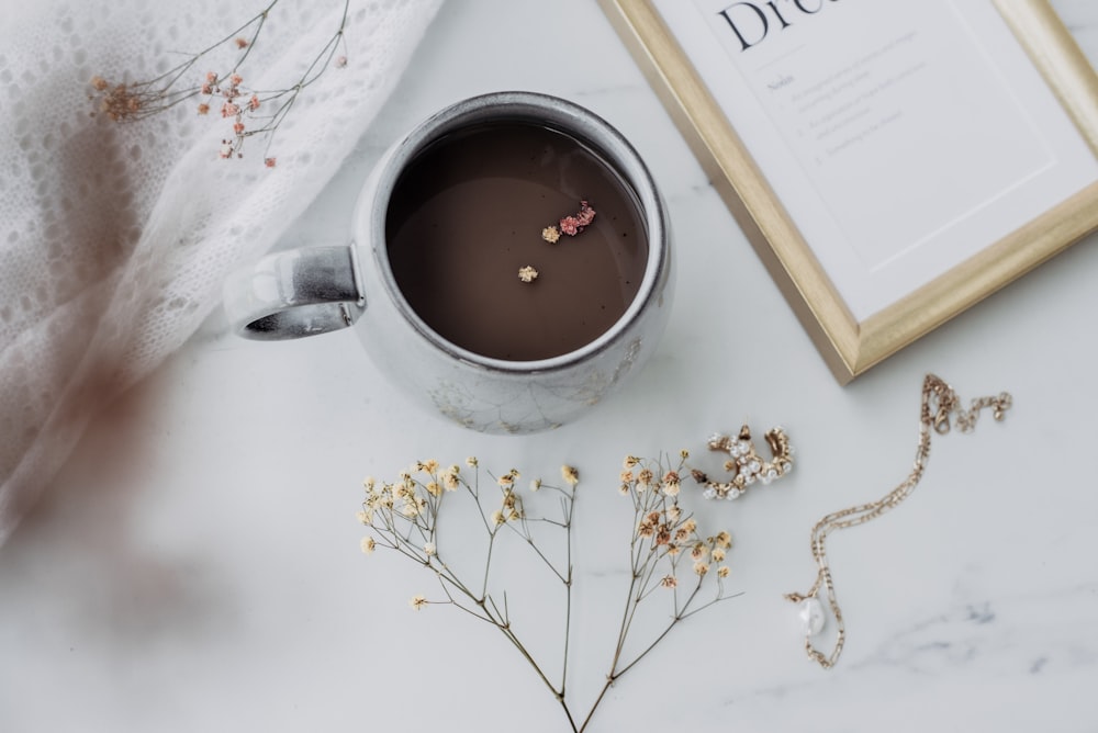 a cup of hot chocolate next to a framed photograph
