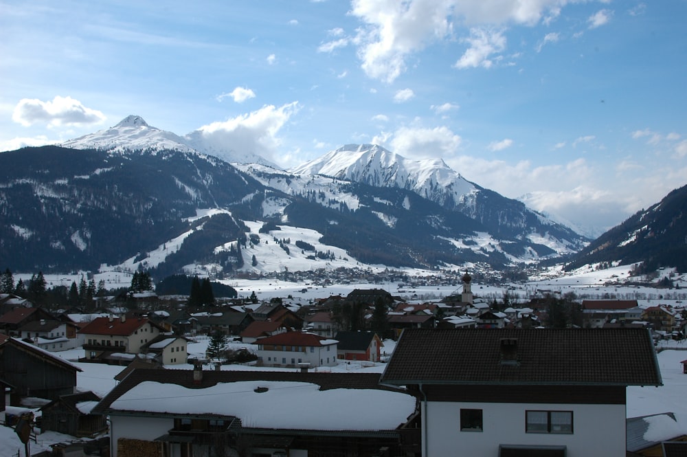 a snow covered mountain range with houses in the foreground