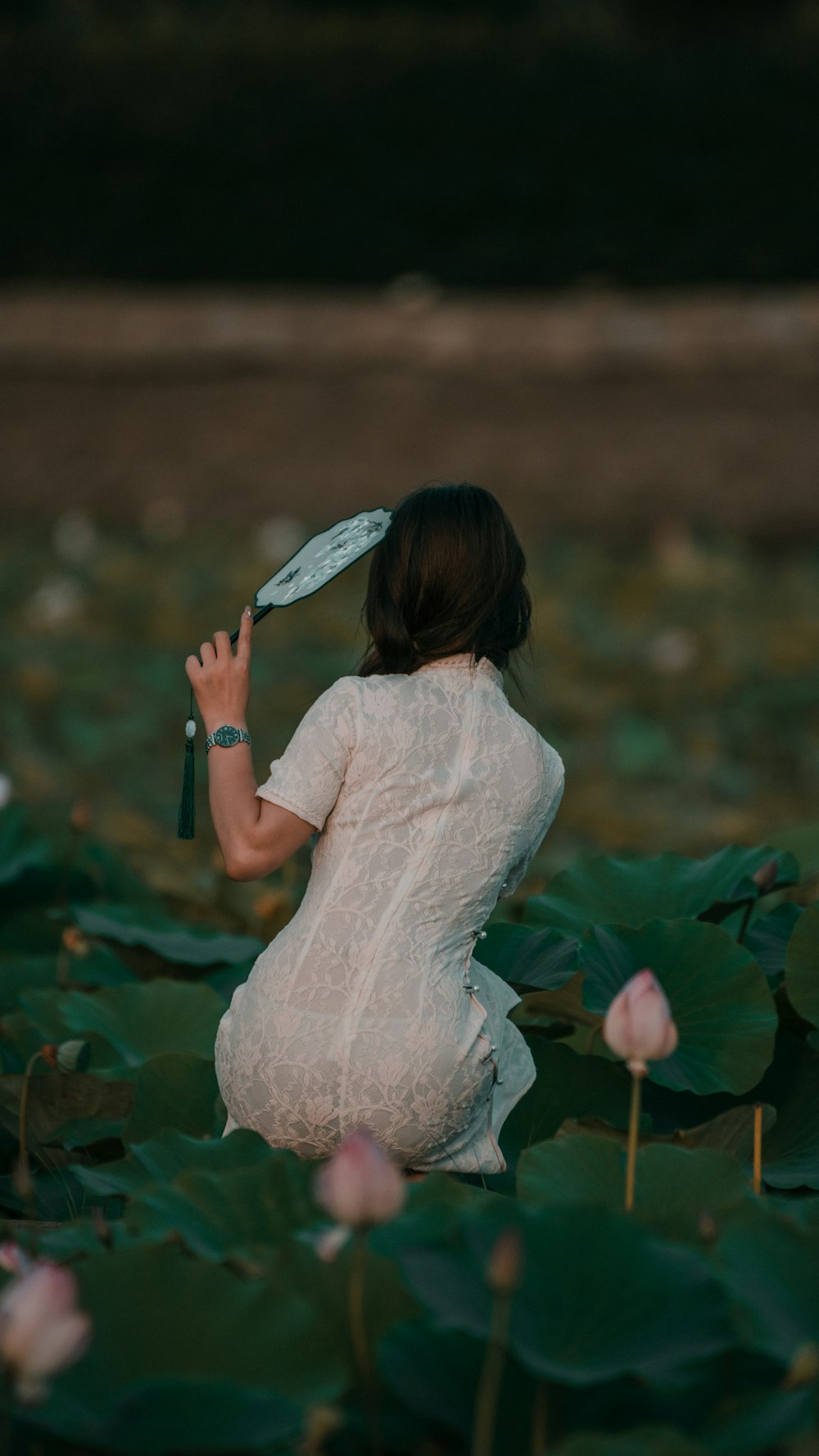 a woman in a white dress sitting on a lily pad