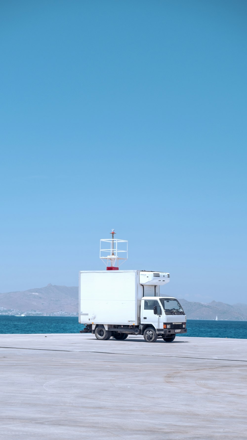 a truck is parked on the beach near the water