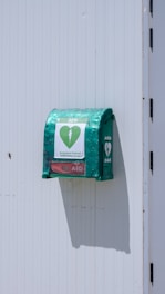 a green mailbox attached to a white wall