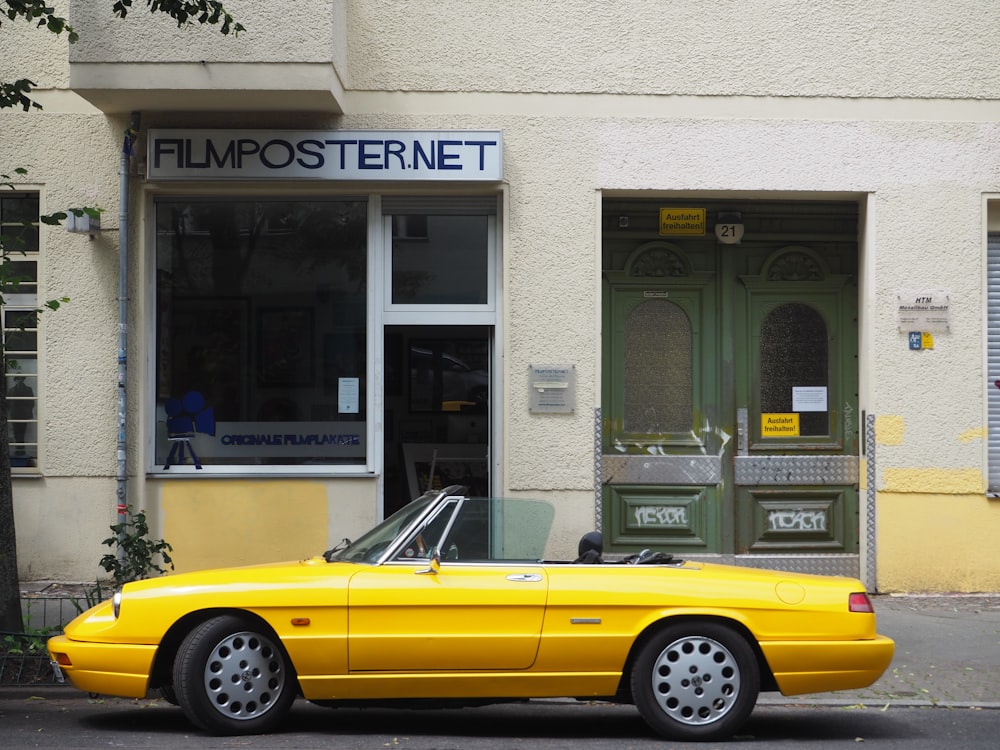 a yellow convertible car parked in front of a building