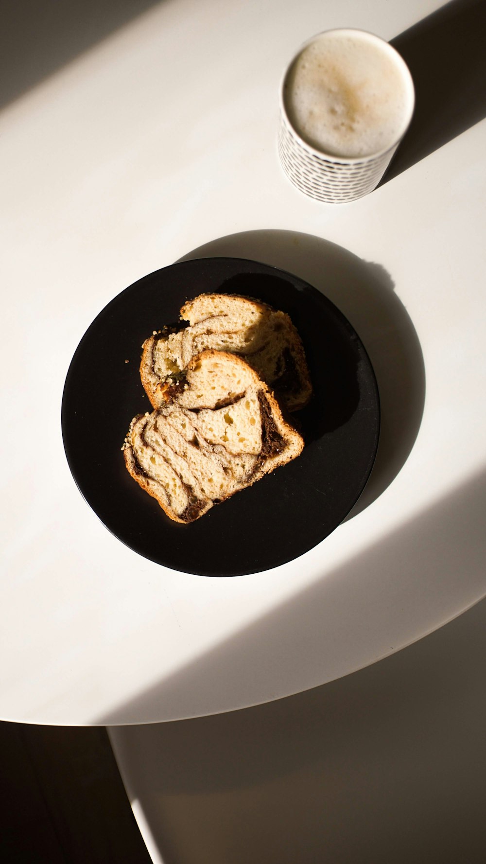 a black plate topped with slices of bread next to a cup of coffee