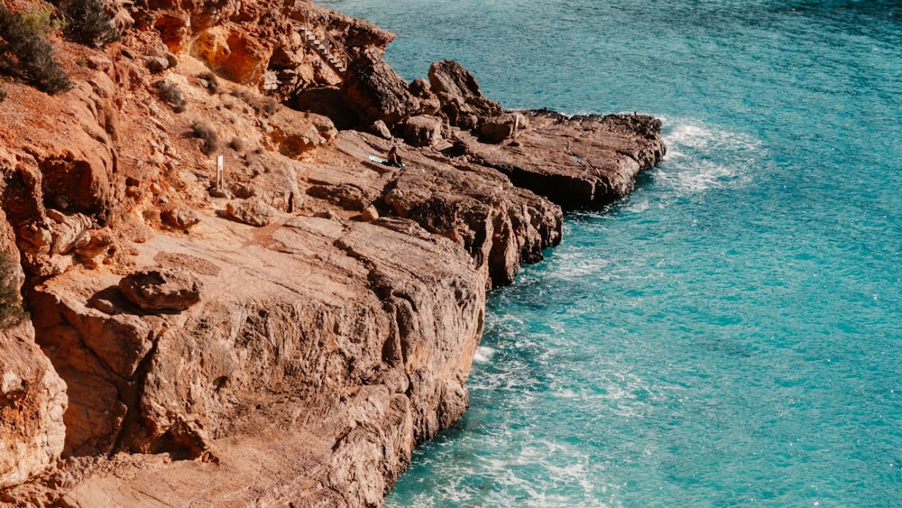 a rocky cliff with a body of water next to it