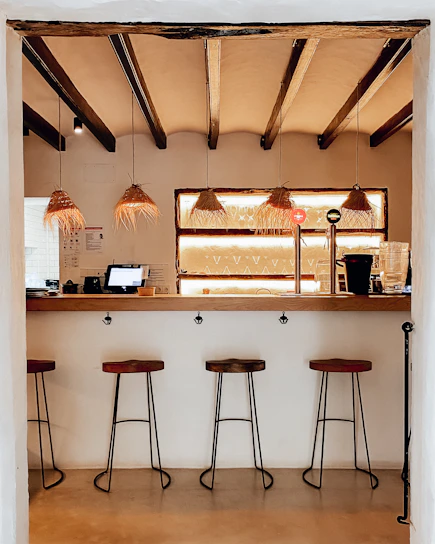 Cozy dimly lit bar counter with seven stools and golden accents.