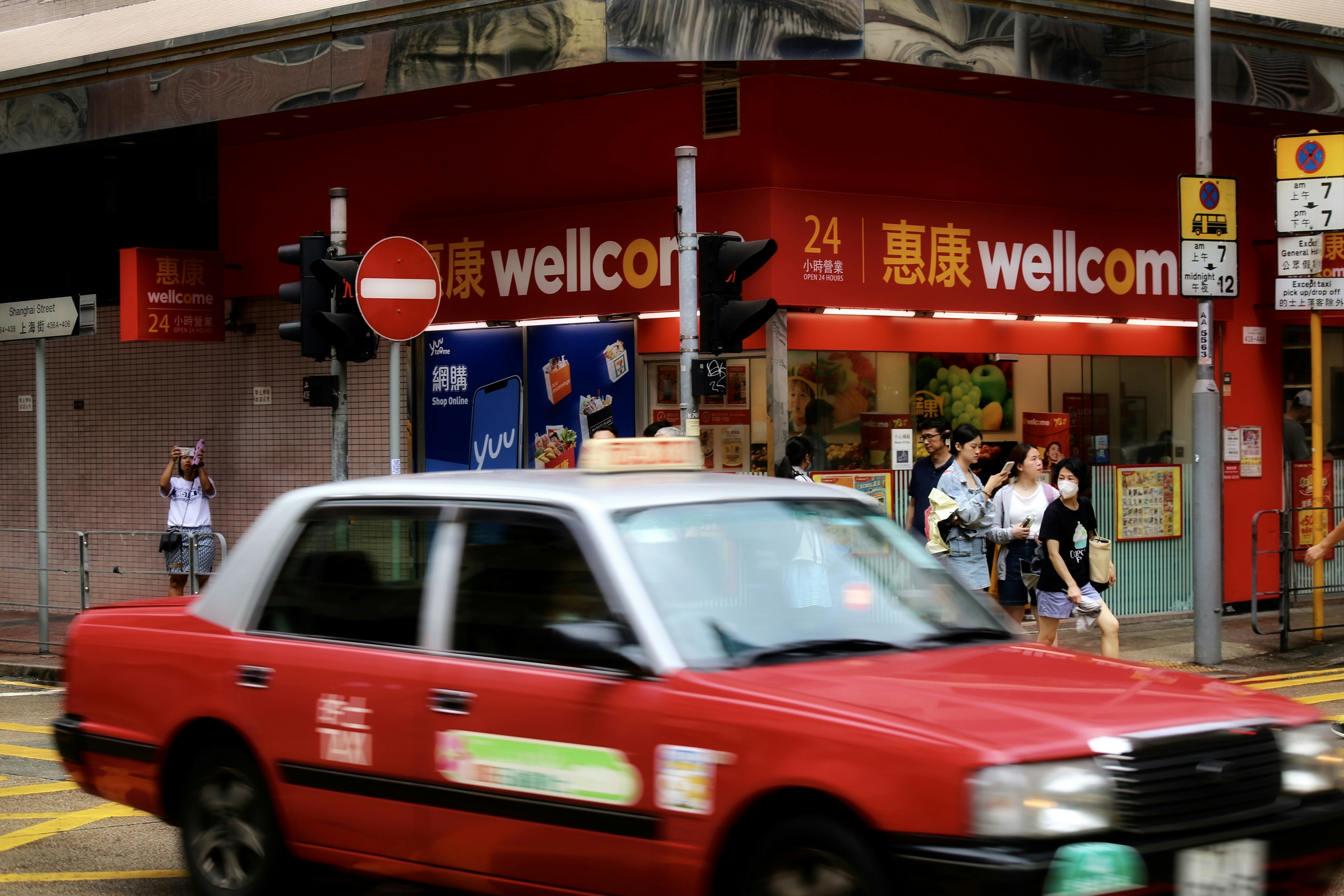 a red taxi cab driving down a street next to a tall red building