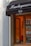 A storefront with a black awning displaying the word 'Hamburguesería'. The window reveals an interior painted in warm tones, possibly a cafe, with a person wearing a red top seated inside.