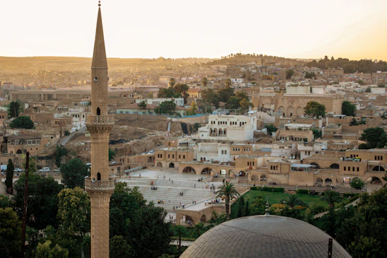 A vibrant view of Mardin's old city with stone houses and a warm sunset in the background.