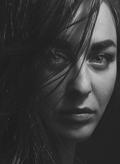 A striking black-and-white portrait of a woman with intense eyes against a dark background.