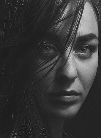 A striking black-and-white portrait of a woman with intense eyes against a dark background.